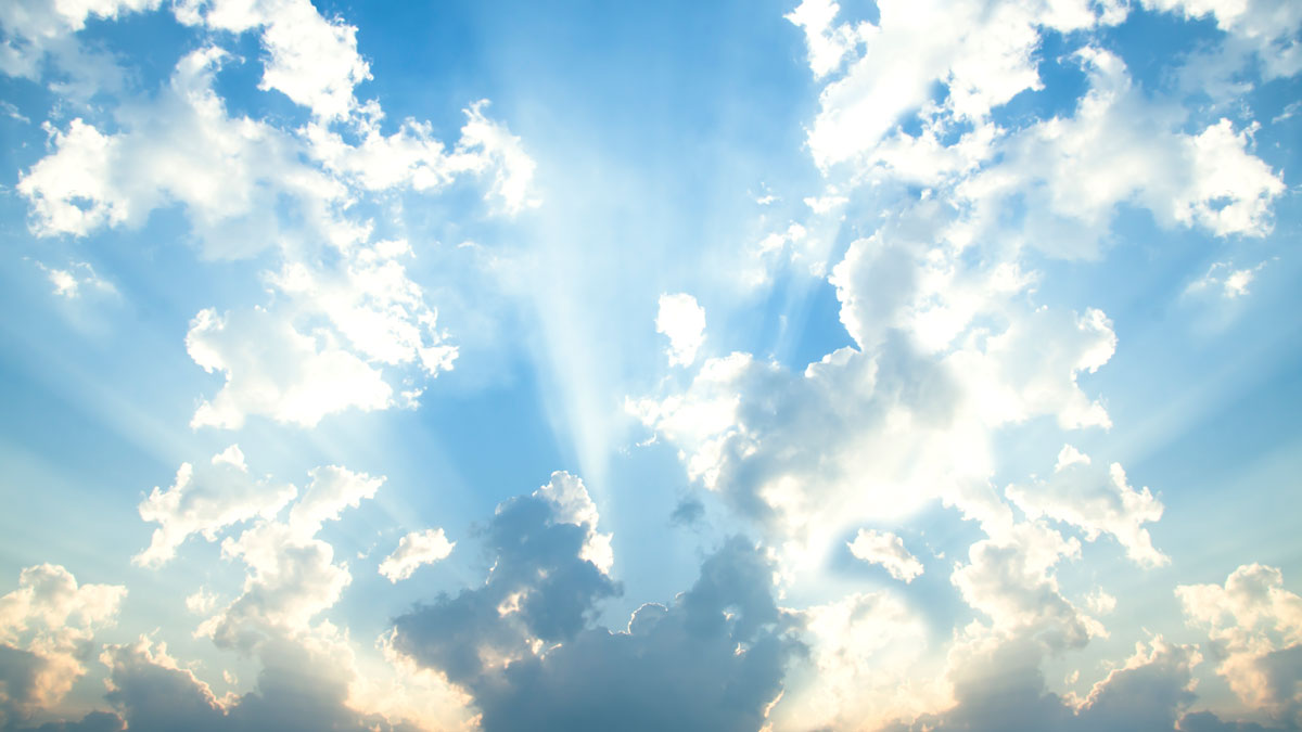 sun shining from behind clouds in blue sky