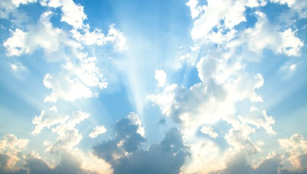 sun shining from behind clouds in blue sky