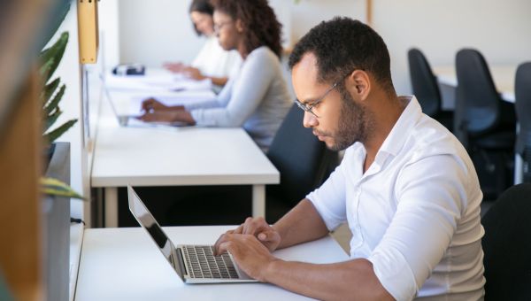 coworkers sitting at desks working on laptops