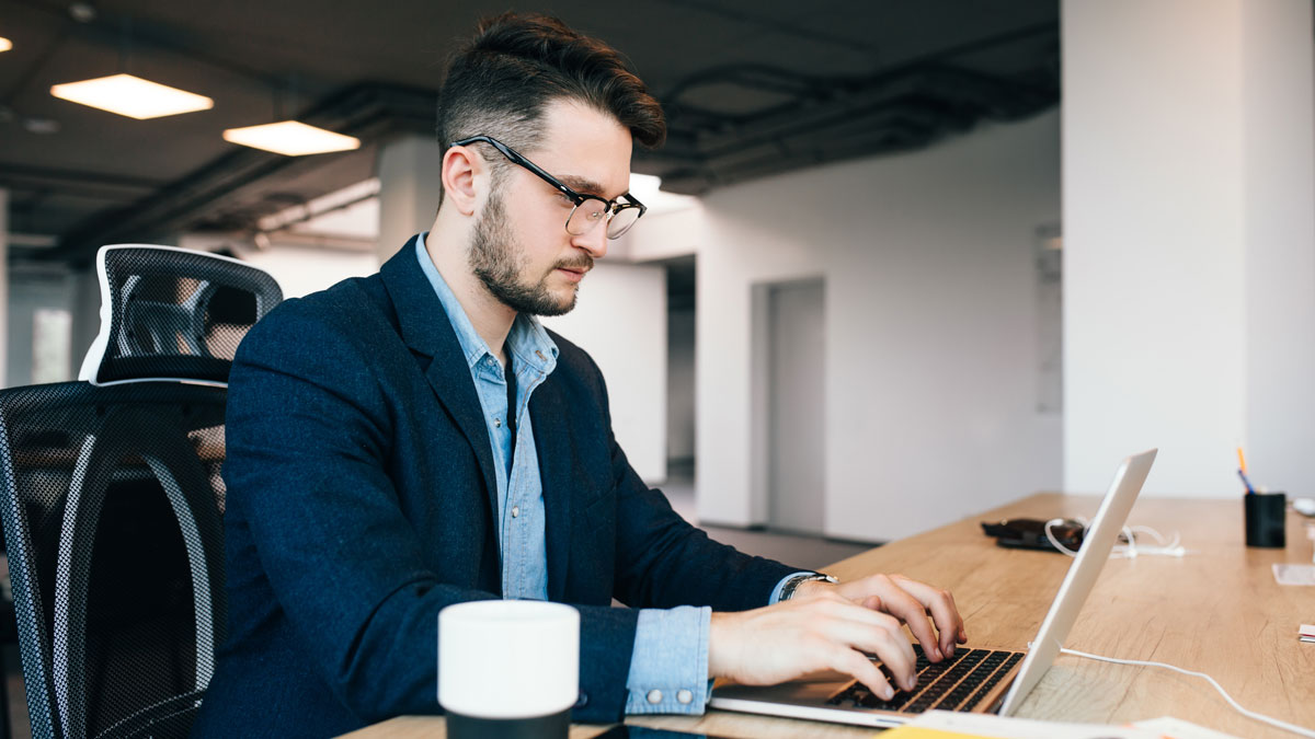 man sitting at table working on a laptop