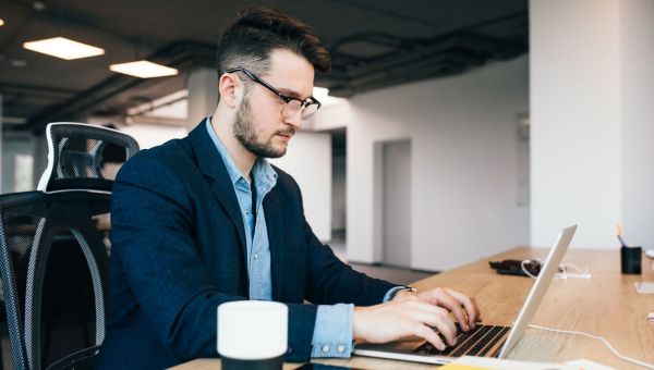 man sitting at table working on a laptop