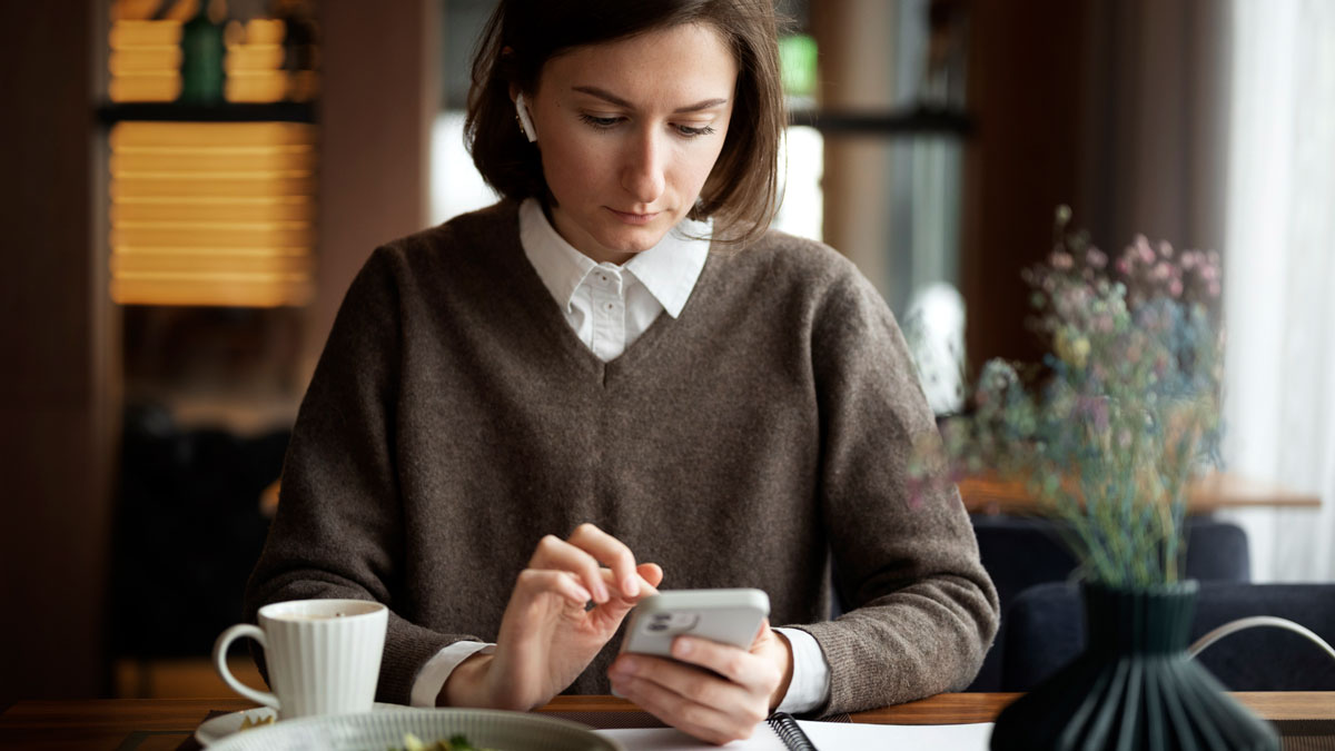 woman sitting in restaurant looking at message on her smartphone