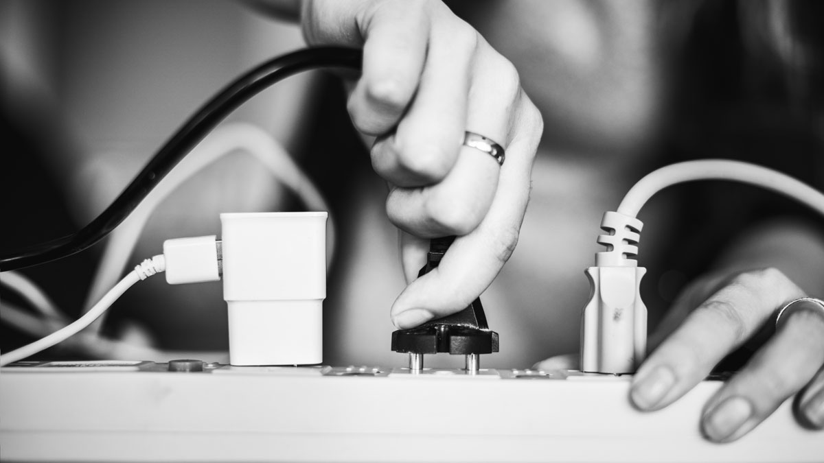 woman plugging in wire to surge protector