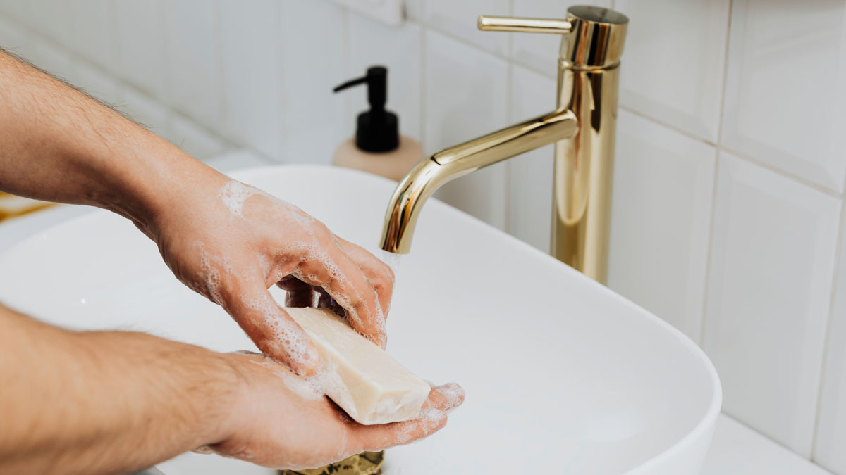 man washing hands in sink using a bar of soap