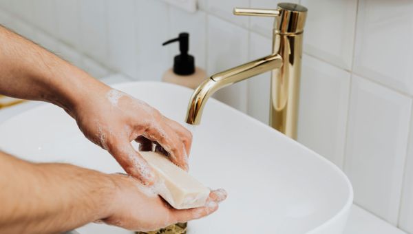 man washing hands in sink using a bar of soap